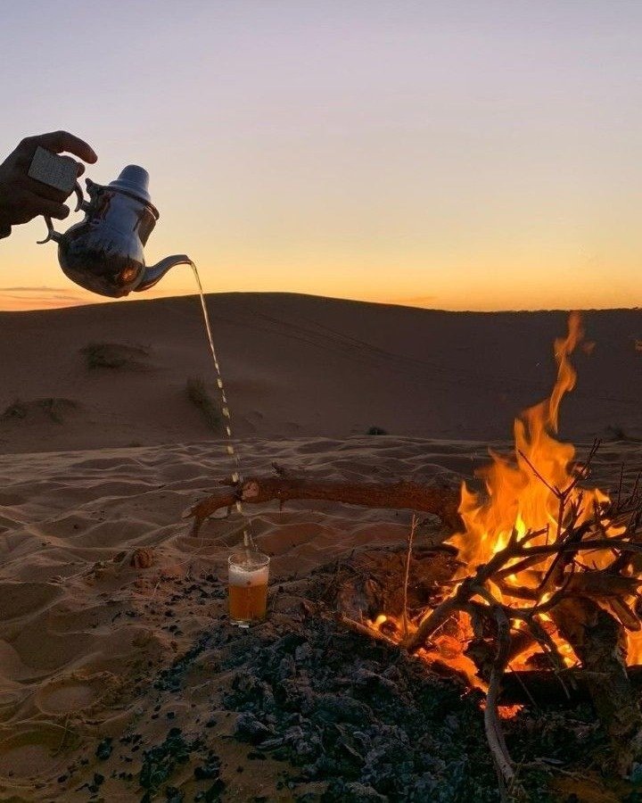 Sahara 5 Hands in indigo robes pouring mint tea from a silver teapot in the Sahara