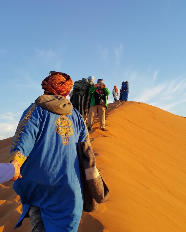 Sahara 6 A woman in a cream headscarf standing beside a camel in the Moroccan desert